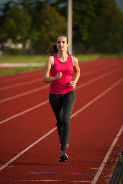 美しい若い女性のランナーは初夏の午後にトラック上で実行されます — ストック写真