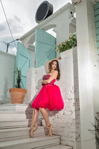 穿着红衣服的年轻漂亮的芭蕾舞演员在白墙后面跳舞 — 图库照片