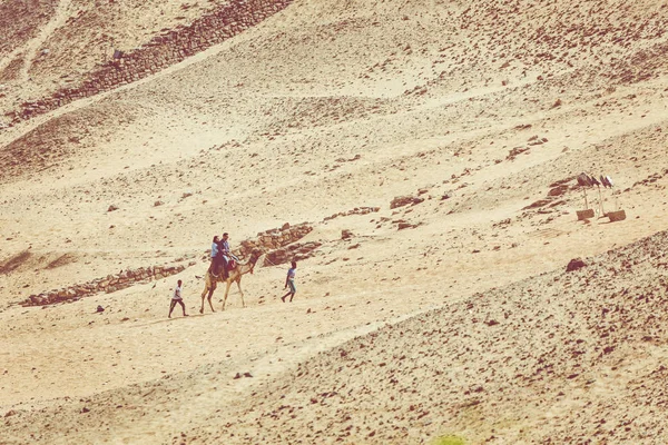 ASWAN, EGIRPT - 24 de marzo de 2017: La gente en la caravana de camellos va —  Fotos de Stock