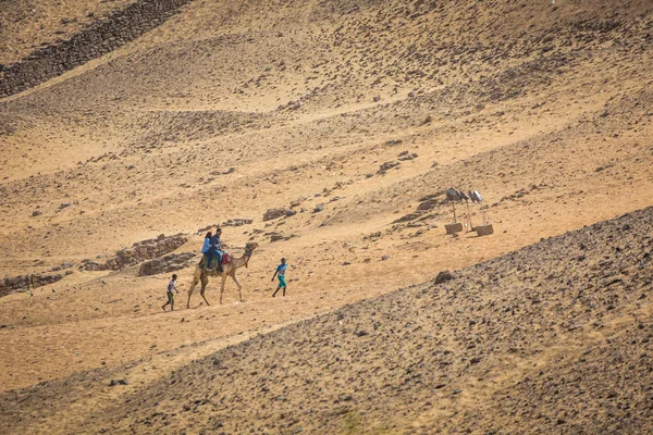 Aswan, Egyrpt - 24 mars 2017: Människor i den kamel karavan goin — Stockfoto