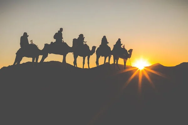 Camel caravan with people going through the sand dunes in the Sa — Stock Photo, Image