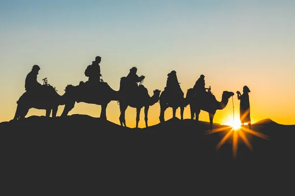 Camel caravan with people going through the sand dunes in the Sa — Stock Photo, Image