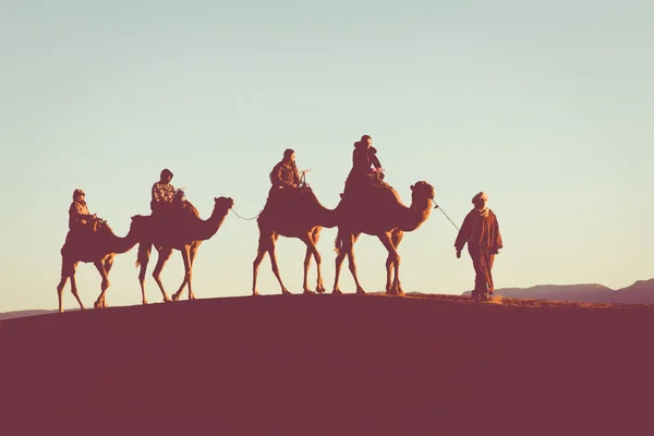 Cammello carovana con persone che attraversano le dune di sabbia nel Sa — Foto Stock