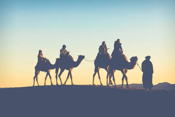 Camel caravan with people going through the sand dunes in the Sa — Stock Photo, Image