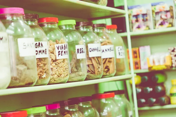 Assortment of glass jars on shelves in herbalist shop on a tradi — Stock Photo, Image