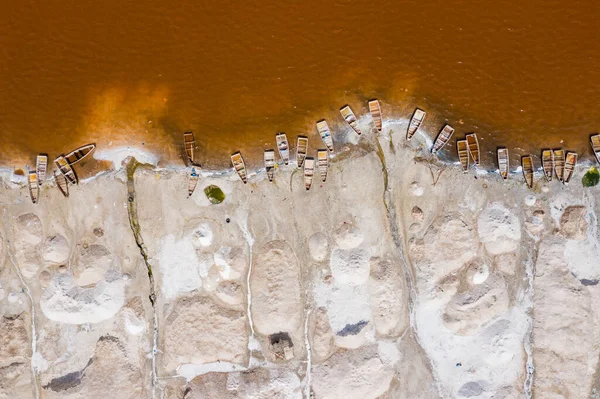 Вид с воздуха на небольшие лодки для сбора соли на розовом озере — стоковое фото