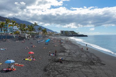 Puerto Naos beach an sunbathing people at beach with black lava 