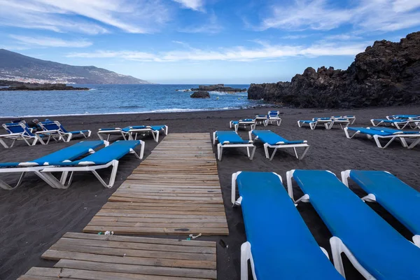 Tumbonas azules y playa de arena negra en Los Cancajos. La Palma, Can —  Fotos de Stock