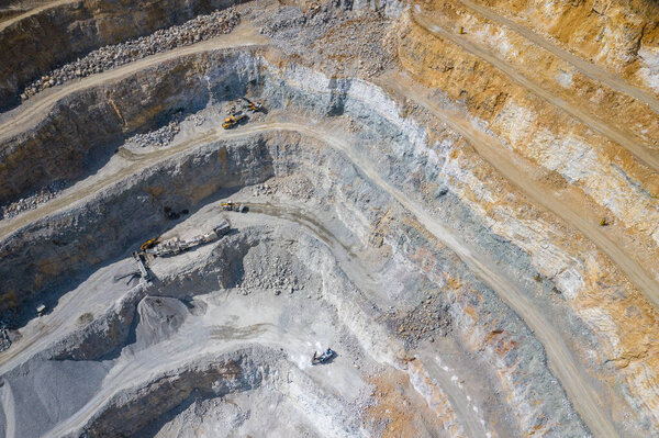Mining from above. Industrial terraces on open pit  mineral mine. Aerial view of opencast mining. Dolomite Mine Excavation. Extractive industry. Giant excavator machinery.