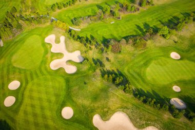 Golf sahasının havadan görünüşü ve kum tuzakları, ağaçlar ve golfçülerle dolu yeşil. 