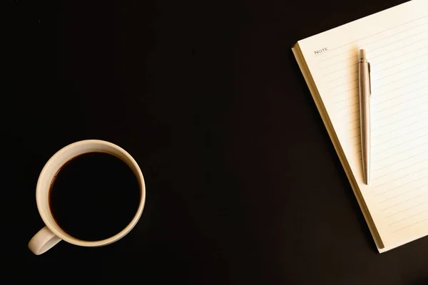 Cuaderno, pluma y café negro en taza blanca . —  Fotos de Stock