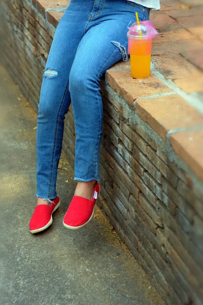 Chica Joven Con Pantalones Vaqueros Rasgados Zapatos Rojos Sentados Pared —  Fotos de Stock