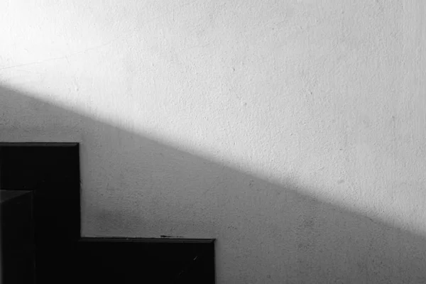 Abstracted light and shadow on the wall next to the stairs, minimalist on black and white geometric style.