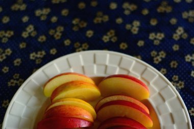 Gala elmalarını mavi arka planda beyaz bir tabakta dilimle.