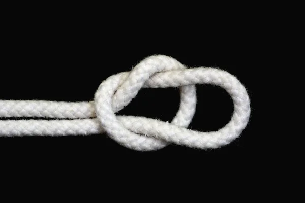 绑在黑色背景上的一条白色绳子 结与跑步结隔离 — 图库照片
