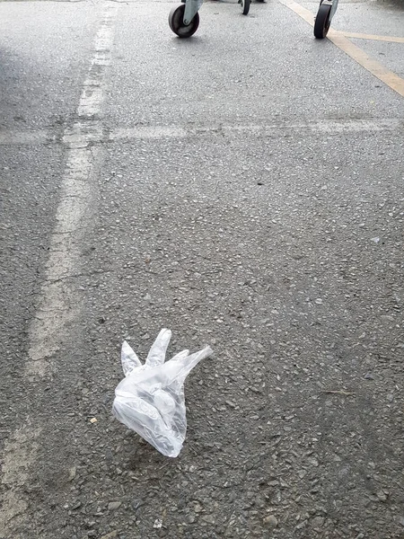 Alışveriş merkezinin asfalt otoparkında plastik eldiven. Soyut arkaplan.