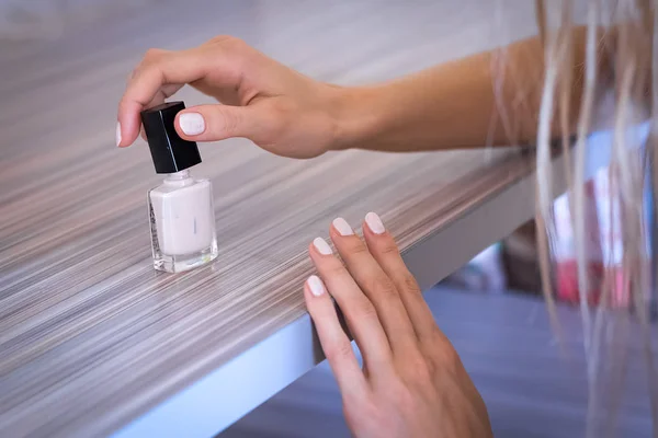woman paints her nails with white paint
