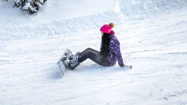 Menina snowboarder caiu e sentado na neve — Fotografia de Stock