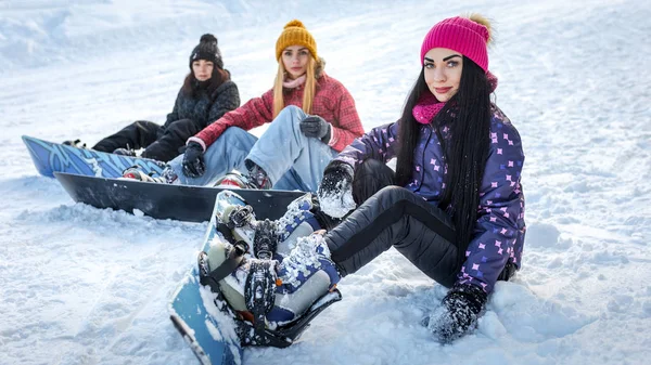 Três meninas snowboarders sentado na neve — Fotografia de Stock