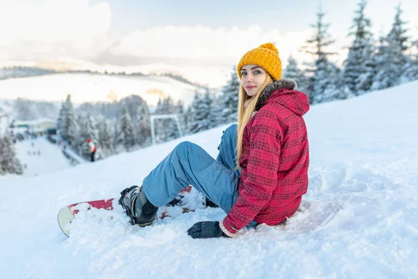 Красива дівчина сноубордист сидить на самоті в снігу на горі на відкритому повітрі, зимові види спорту — стокове фото