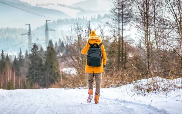 Osamělý turistický cestovatel v zimních lesích s batohem na zasněžené cestě ven — Stock fotografie