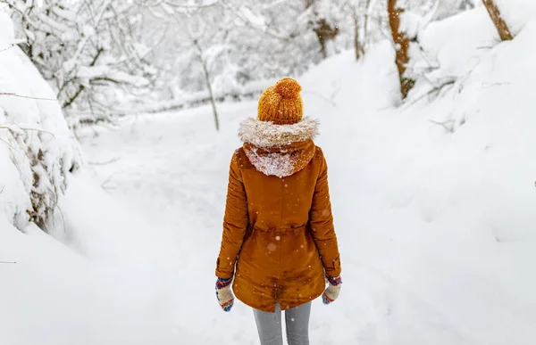 Дівчина або жінка ходять взимку на відкритому повітрі, сніжна холодна погода, снігопад в сільській місцевості, жовтий капелюх — стокове фото