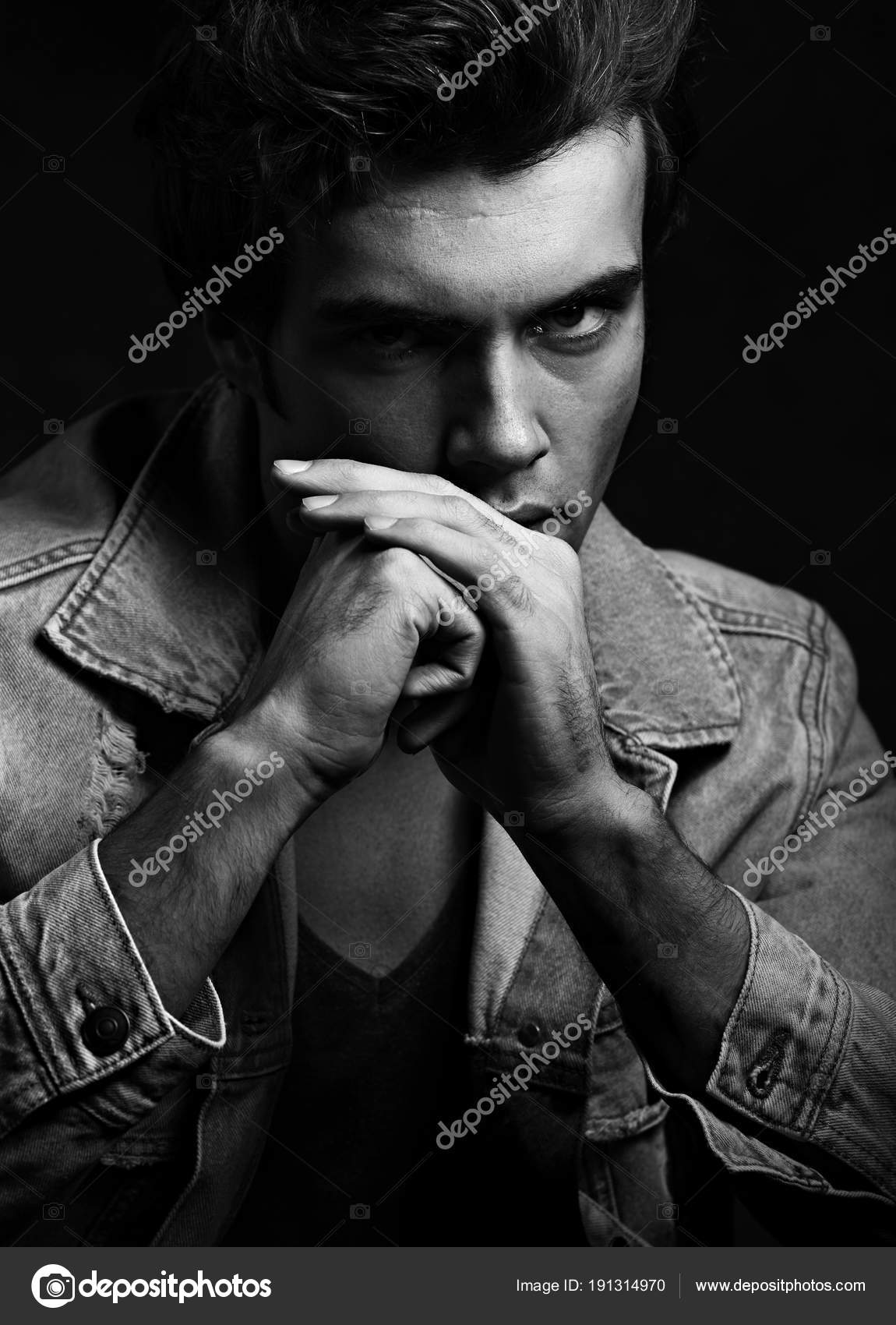 Handsome thinking male model posing in fashion blue jeans jacket looking on dark shadow background closeup black and white portrait photo by nastia1983