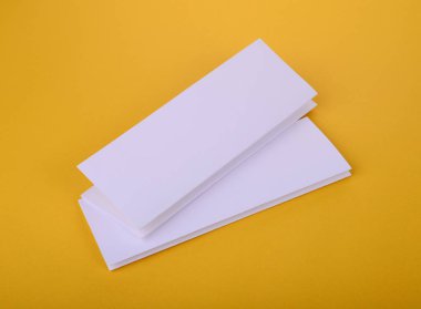 iki beyaz kağıt dört kat broşürü mockup Sarı zemin üzerine