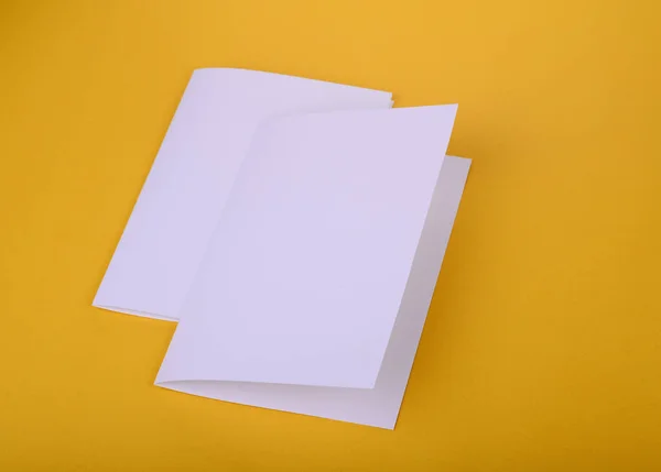 Dos bifold de papel blanco folleto maqueta sobre fondo amarillo — Foto de Stock