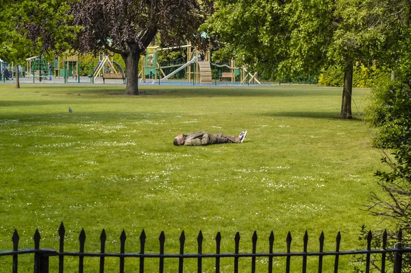 Homem deitado no gramado enquanto descansa e relaxa no parque . — Fotografia de Stock