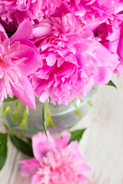 Peonías rosadas en jarrón sobre superficie de madera blanca —  Fotos de Stock