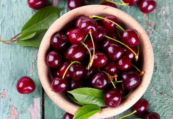 Cerezas en un tazón sobre una superficie de madera — Foto de Stock