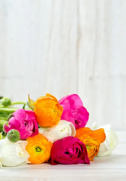 木製のテーブルに白、ピンク、オレンジのキンポウゲの花束 — ストック写真