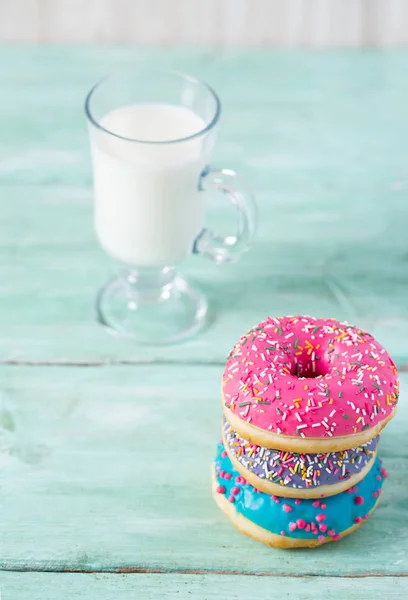 Rosquillas coloridas y vaso de leche — Foto de Stock