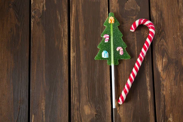 Bastón de caramelos rayado y árbol de Navidad en la superficie de madera — Foto de Stock