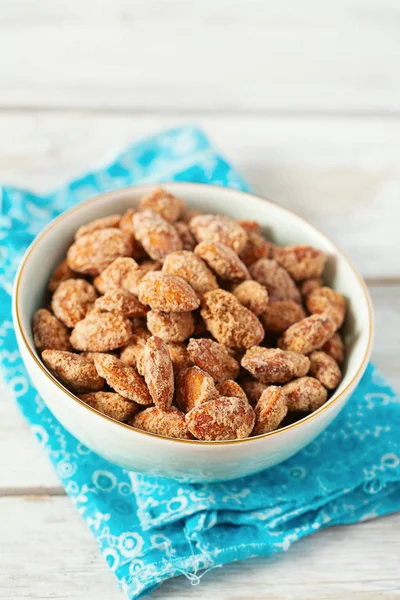 Caramelized almonds on white wooden surface — Stock Photo, Image