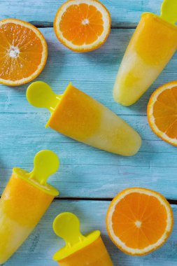 Ev yapımı turuncu çubuklu dondurmayı turkuaz ahşap yüzey üzerinde