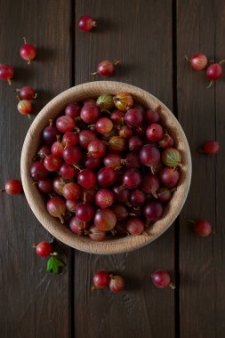 Ahşap yüzeyde bir kasede kırmızı bektaşi üzümü