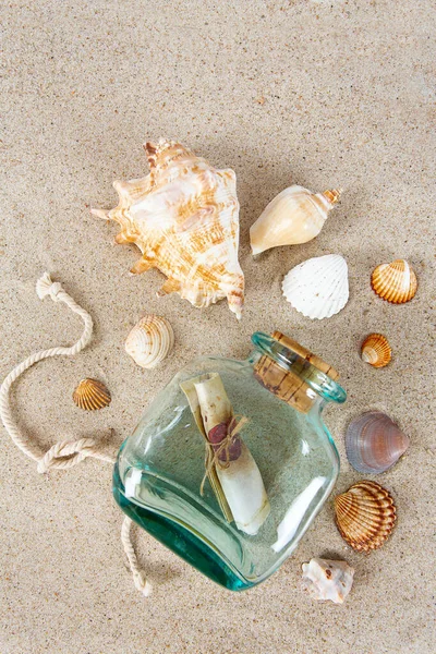 message in a bottle, sea shells and pebbles on sand