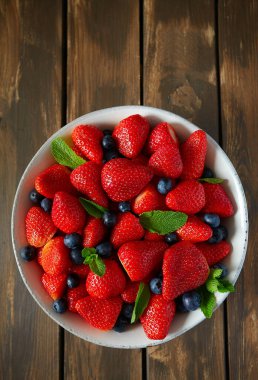 Koyu ahşap yüzeyde taze çilekler.