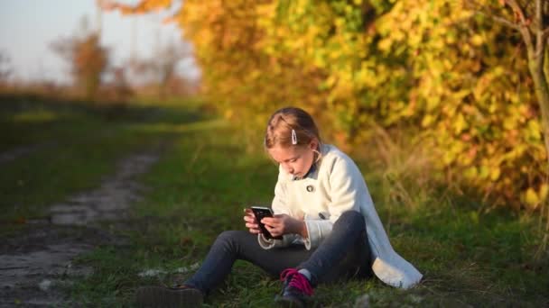 Молодая девушка делает селфи в осеннем лесу — стоковое видео