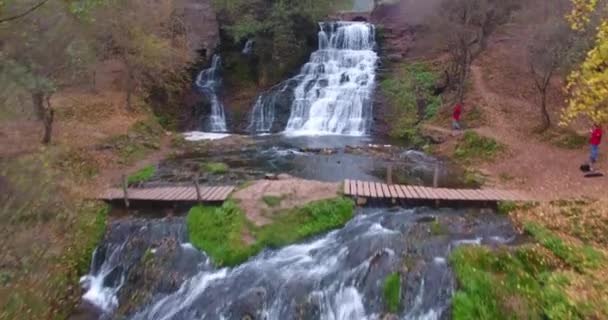 Images aériennes survolant une belle cascade avec de la mousse, de l'herbe verte, des arbres forestiers et des pierres avec des rochers. Ukraine — Video