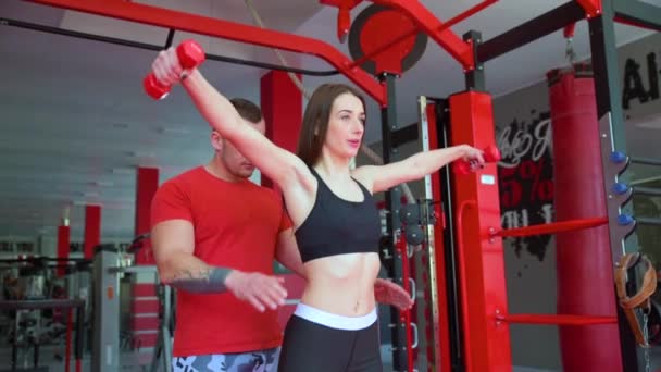 Entrenador de gimnasio que muestra a los aprendices cómo levantar pesas, hacer ejercicio en pareja juntos — Vídeos de Stock