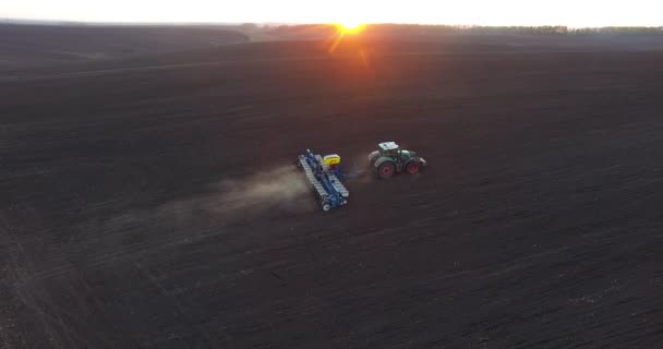 Oversikt over traktorer som planter hvete ved solnedgang – stockvideo