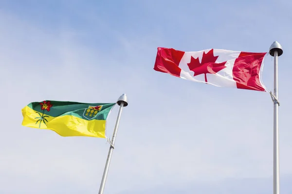 Bandeiras de Saskatchewan e Canadá contra o céu azul — Fotografia de Stock