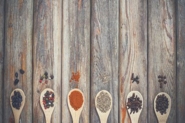 Farklı baharatlar ve tuz ahşap bir masada, tahta kaşıklarda yatıyor.
