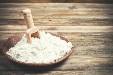 Ekmek pişirmek için un ve buğday başakları ahşap bir yüzeyde yatar.