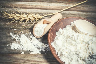 Ekmek pişirmek için un ve buğday başakları ahşap bir yüzeyde yatar.