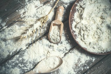 Ekmek pişirmek için un ve buğday başakları ahşap bir yüzeyde yatar.