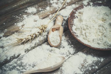 Ekmek pişirmek için un ve buğday başakları ahşap bir yüzeyde yatar.
